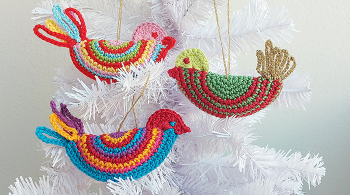 Three colorful crochet bird ornaments in white Christmas tree